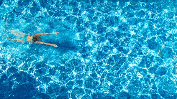 在游泳池里活跃的女孩从上面俯瞰着空中无人飞机 年轻女人在蓝色的水里游泳 热带假期 度假的概念 — 图库照片