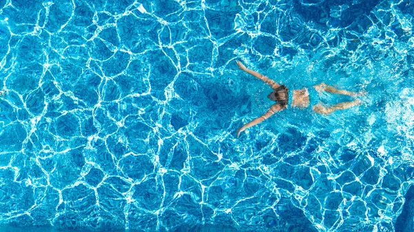 在游泳池里活跃的女孩从上面俯瞰着空中无人飞机 年轻女人在蓝色的水里游泳 热带假期 度假的概念 — 图库照片