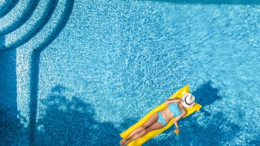 Güzel genç kız rahatlatıcı yüzme havuzunda şişme yatak üzerinde yüzüyor ve aile tatil tropikal tatil, hava uçak görünümü yukarıdan su eğlence var