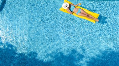 Güzel genç kız rahatlatıcı yüzme havuzunda şişme yatak üzerinde yüzüyor ve aile tatil tropikal tatil, hava uçak görünümü yukarıdan su eğlence var