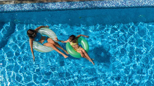 Havuz manzaralı aktif çocuklar, mutlu çocuklar şişirilebilir halka çöreklerle yüzerler ve tatilde aile tatilinde suda eğlenirler.