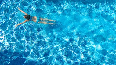 Yüzme havuzundaki aktif kız yukarıdan drone görüntüsü, mavi suda yüzen genç kadın, tropikal tatil, tatil konseptinde tatil