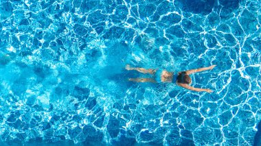 Yüzme havuzundaki aktif kız yukarıdan drone görüntüsü, mavi suda yüzen genç kadın, tropikal tatil, tatil konseptinde tatil