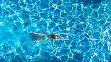 Yüzme havuzundaki aktif kız yukarıdan drone görüntüsü, mavi suda yüzen genç kadın, tropikal tatil, tatil konseptinde tatil
