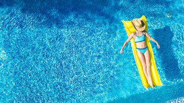 Yüzme havuzunda dinlenen bir kız, şişme yatakta yüzen bir çocuk ve aile tatilinde suda eğlenen bir kız, tropik tatil beldesi, yukarıdan gelen hava aracı manzarası.