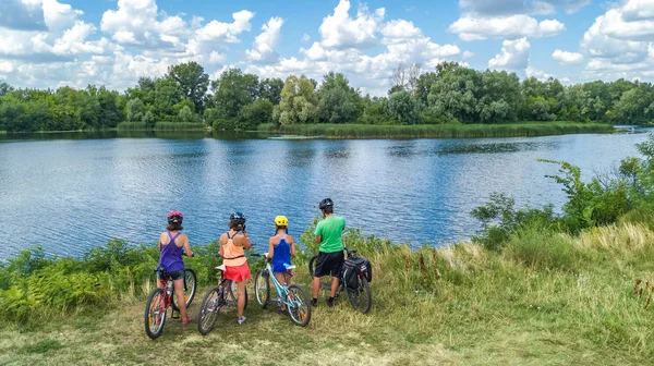 屋外での自転車サイクリング 自転車での積極的な親と子供 美しい川の近くでリラックスした子供たちと幸せな家族の空中ビュー スポーツとフィットネスのコンセプト — ストック写真