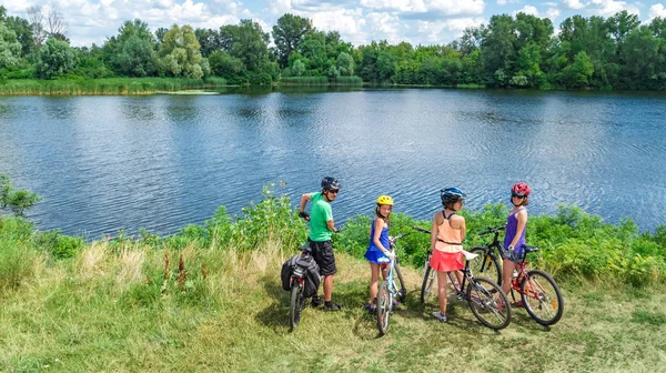 骑自行车的家庭在户外骑车 活跃的父母和骑自行车的孩子 从空中观察孩子们在美丽的河边放松的快乐家庭 体育和健身的概念 — 图库照片