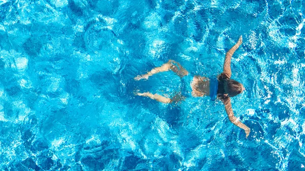 Yüzme havuzundaki aktif kız yukarıdan drone görüntüsü, mavi suda yüzen genç kadın, tropikal tatil, tatil konseptinde tatil