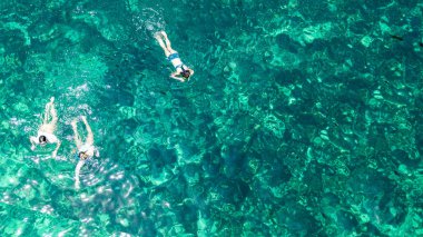 Yukarıdan şnorkel aile havadan üst görünümü, anne ve çocuklar Tayland yaz tatili sırasında mercan ile berrak bir tropikal deniz suyunda yüzme şnorkel