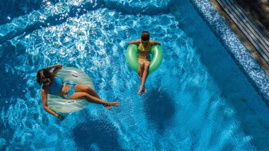 Havuz manzaralı aktif çocuklar, mutlu çocuklar şişirilebilir halka çöreklerle yüzerler ve tatilde aile tatilinde suda eğlenirler.