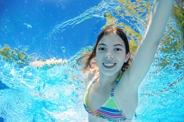 Çocuk yüzme havuzunda su altında yüzüyor, mutlu aktif genç kız dalıyor ve su altında eğleniyor, çocuk fitness ve tatil beldesinde aile tatilinde spor yapıyor.