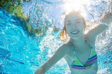 Çocuk yüzme havuzunda su altında yüzüyor, mutlu aktif genç kız dalıyor ve su altında eğleniyor, çocuk fitness ve tatil beldesinde aile tatilinde spor yapıyor.