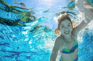 Çocuk yüzme havuzunda su altında yüzüyor, mutlu aktif genç kız dalıyor ve su altında eğleniyor, çocuk fitness ve tatil beldesinde aile tatilinde spor yapıyor.