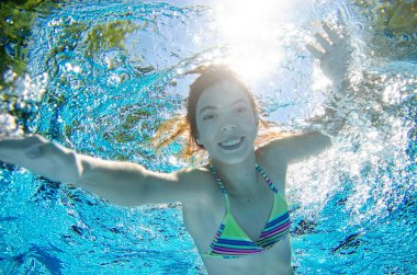 Çocuk yüzme havuzunda su altında yüzüyor, mutlu aktif genç kız dalıyor ve su altında eğleniyor, çocuk fitness ve tatil beldesinde aile tatilinde spor yapıyor.