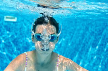 Çocuk yüzme havuzunda su altında yüzüyor, mutlu aktif genç kız dalıyor ve su altında eğleniyor, çocuk fitness ve tatil beldesinde aile tatilinde spor yapıyor.