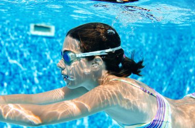 Çocuk yüzme havuzunda su altında yüzüyor, mutlu aktif genç kız dalıyor ve su altında eğleniyor, çocuk fitness ve tatil beldesinde aile tatilinde spor yapıyor.