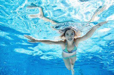 Çocuk yüzme havuzunda su altında yüzüyor, mutlu aktif genç kız dalıyor ve su altında eğleniyor, çocuk fitness ve tatil beldesinde aile tatilinde spor yapıyor.