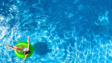 Yüzme havuzundaki aktif genç kız yukarıdan havuz manzaralı, çocuk gevşiyor ve şişme halka donutla yüzüyor ve aile tatilinde suda eğleniyor, tropikal tatil beldesi
