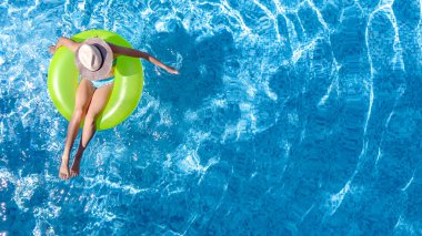 Yukarıdan yüzme havuzu havadan üst görünümünde şapka aktif genç kız, çocuk rahatlatır ve şişme halka donut üzerinde yüzer ve aile tatilinde suda eğleniyor, tropikal tatil beldesi