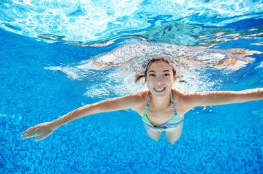 Çocuk yüzme havuzunda su altında yüzüyor, mutlu aktif genç kız dalıyor ve su altında eğleniyor, çocuk fitness ve tatil beldesinde aile tatilinde spor yapıyor.