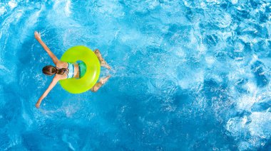 Yüzme havuzundaki aktif genç kız yukarıdan havuz manzaralı, çocuk gevşiyor ve şişme halka donutla yüzüyor ve aile tatilinde suda eğleniyor, tropikal tatil beldesi
