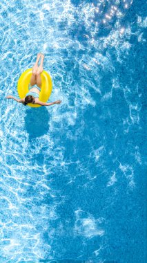 Yüzme havuzundaki aktif genç kız yukarıdan havuz manzaralı, çocuk gevşiyor ve şişme halka donutla yüzüyor ve aile tatilinde suda eğleniyor, tropikal tatil beldesi