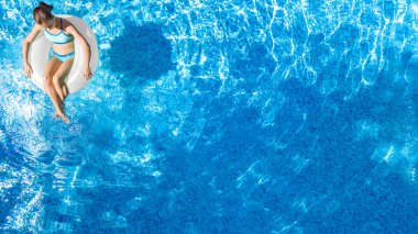 Yüzme havuzundaki aktif genç kız yukarıdan havuz manzaralı, çocuk gevşiyor ve şişme halka donutla yüzüyor ve aile tatilinde suda eğleniyor, tropikal tatil beldesi