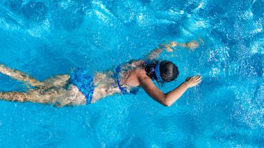 Yüzme havuzundaki aktif kız yukarıdan drone görüntüsü, mavi suda yüzen genç kadın, tropikal tatil, tatil konseptinde tatil