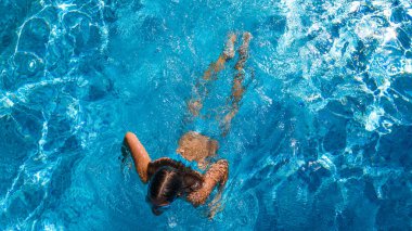 Yüzme havuzundaki aktif kız yukarıdan drone görüntüsü, mavi suda yüzen genç kadın, tropikal tatil, tatil konseptinde tatil