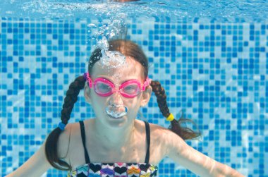 Çocuk yüzme havuzunda su altında yüzüyor, gözlüklü mutlu aktif kız dalıyor ve su altında eğleniyor, çocuk fitness ve tatil beldesinde aile tatilinde spor yapıyor.