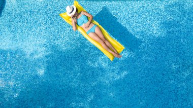 Yüzme havuzunda dinlenen güzel bir genç kız, şişme yatakta yüzen ve aile tatilinde suda eğlenen bir kadın, tropikal tatil beldesi, yukarıdan drone manzarası