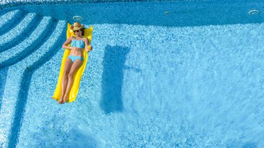 Yüzme havuzunda dinlenen güzel bir genç kız, şişme yatakta yüzen ve aile tatilinde suda eğlenen bir kadın, tropikal tatil beldesi, yukarıdan drone manzarası