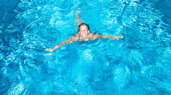 Активная девушка в бассейне беспилотник вид сверху, молодая женщина плавает в голубой воде, тропический отдых, отдых на курорте концепции
