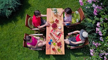 Aile ve arkadaşlar yaz bahçe partisinde dışarıda birlikte yemek yiyorlar. Yukarıdan yiyecek ve içeceklerle dolu bir masa manzarası. Tatil, tatil ve piknik konsepti.