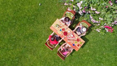 Aile ve arkadaşlar yaz bahçe partisinde dışarıda birlikte yemek yiyorlar. Yukarıdan yiyecek ve içeceklerle dolu bir masa manzarası. Tatil, tatil ve piknik konsepti.