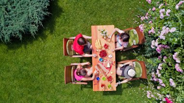 Aile ve arkadaşlar yaz bahçe partisinde dışarıda birlikte yemek yiyorlar. Yukarıdan yiyecek ve içeceklerle dolu bir masa manzarası. Tatil, tatil ve piknik konsepti.