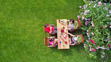 Aile ve arkadaşlar yaz bahçe partisinde dışarıda birlikte yemek yiyorlar. Yukarıdan yiyecek ve içeceklerle dolu bir masa manzarası. Tatil, tatil ve piknik konsepti.