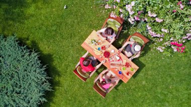 Aile ve arkadaşlar yaz bahçe partisinde dışarıda birlikte yemek yiyorlar. Yukarıdan yiyecek ve içeceklerle dolu bir masa manzarası. Tatil, tatil ve piknik konsepti.