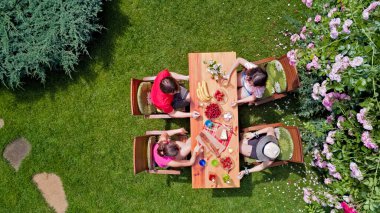 Aile ve arkadaşlar yaz bahçe partisinde dışarıda birlikte yemek yiyorlar. Yukarıdan yiyecek ve içeceklerle dolu bir masa manzarası. Tatil, tatil ve piknik konsepti.