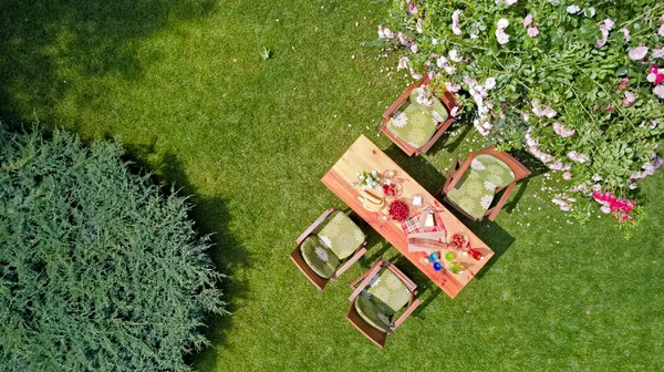 装饰桌子 草莓和水果在美丽的夏天玫瑰花园 空中俯瞰桌上食物和饮料设置从上方 与家人和朋友一起休闲和野餐 — 图库照片