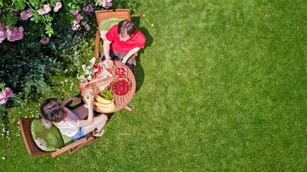 ロマンチックなデートで美しいバラの庭で食べ物や飲み物を楽しむ若いカップル 公園で一緒に屋外で食事や飲み物を食べる男女の上からの空中トップビュー — ストック写真