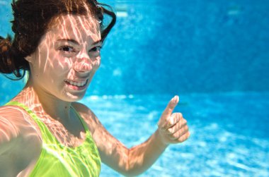 Çocuk yüzme havuzunda su altında yüzüyor, mutlu aktif genç kız dalıyor ve su altında eğleniyor, çocuk fitness ve tatil beldesinde aile tatilinde spor yapıyor.