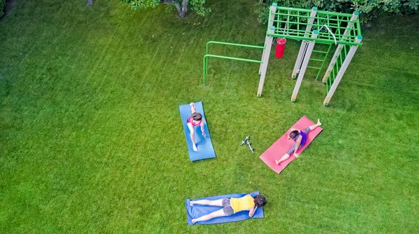Family fitness and sport outdoors, group of active girls doing workout in park, aerial top view from above