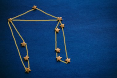 Mavi arka planda Terazi burcu işareti, şematik bir resim. Doğum tarihine göre geleceği tahmin etmek, bir yıldız falı derlemek. Resim yazar tarafından yapılmıştır..