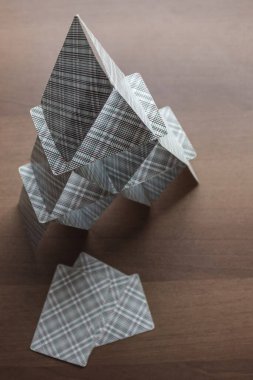 Kahverengi masada kağıt oynamak. Sakin ol, iskambil kağıdından ev. Güvenilmezlik, dayanaksızlık, boş planlar, beyhudelik. Üst görünüm, gündüz kenarı aydınlatma.