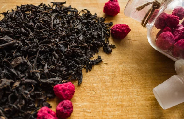 黒茶の原料は 伝統的な熱い飲み物を調理します お茶の木の大規模な 選択された葉は 最高級 ガラス瓶で ラズベリーを乾燥させます 木造背景 — ストック写真