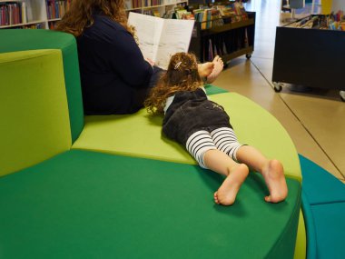 Küçük kız ve annesi birlikte evde bir kanepe kalite zamanında yalan sırasında bir kitap okuma