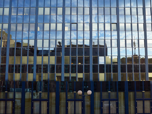 Corporate modern office building with glass windows and reflection of sky