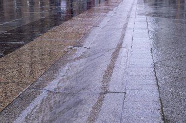Yağmurlu bir günde kaldırım taşlı kaldırımda su akan kentsel sokak oluğu. arkaplan, hava.