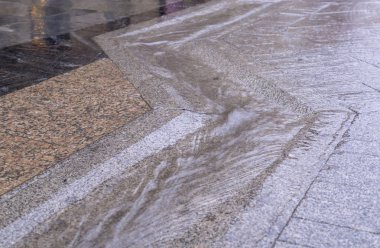 Yağmurlu bir günde kaldırım taşlı kaldırımda su akan kentsel sokak oluğu. arkaplan, hava.